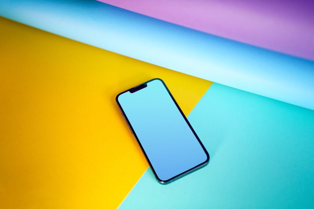 Modern smartphone lies on a vivid, colorful background, emphasizing technology and design.